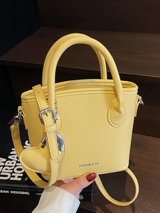 Chic yellow lychee texture bucket bag with dual handles and heart charm accessory