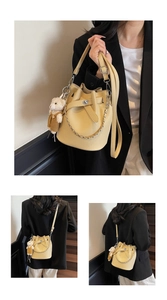 Detail der beigen Eimertasche mit Litschi-Struktur, Kette und Teddybären-Anhänger