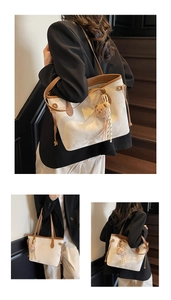 Detailed view of a white large tote bag with brown leather trim and a bear charm
