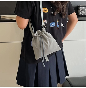 Close-up of gray nylon drawstring bag showing the side brand label and soft fabric texture