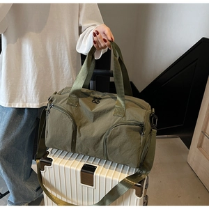 Detail of dark green nylon duffle bag with multiple pockets on a white suitcase
