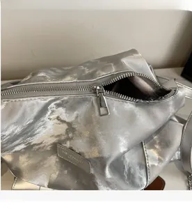 Close-up of smooth metal zipper and silver crinkled texture on retro tote bag
