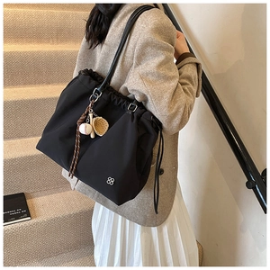 Close-up of black drawstring tote bag with decorative metal flower and baseball charms