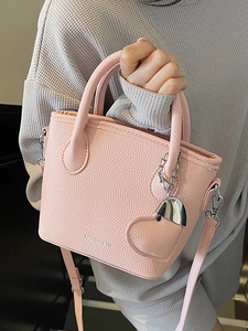 Pink lychee texture bucket bag with adjustable strap and heart-shaped pendant detail