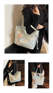 Detail of light blue leather tote bag with pink scarf bear charm and long shoulder straps