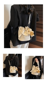 Detail der cremeweißen Beuteltasche mit Litschistruktur, Metallkette und Bärenanhänger
