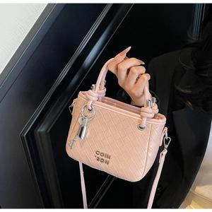 Detail of pink woven leather bucket bag with silver logo and decorative key charm