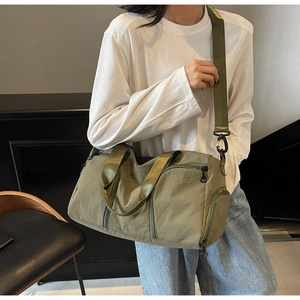 Olive green nylon travel bag with shoe compartment shown on model in a modern room