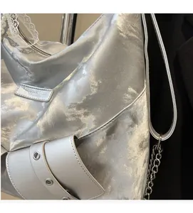 Detail of silver cloud-textured tote bag featuring metal chain and pearl lace charm
