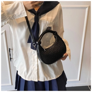 Close-up of black woven crescent bag featuring a spherical handle detail and leather strap