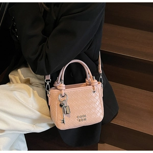 Detail of woven texture bucket bag in light pink with silver key and lock charms