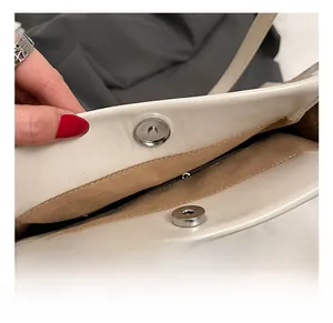 Close-up of bright silver magnetic buckle closure and tan suede lining on the tote bag