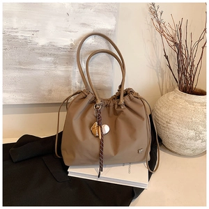Detail view of khaki drawstring tote bag with decorative baseball glove charm