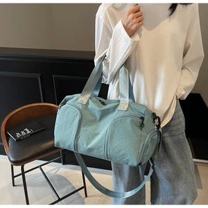 Water-resistant blue nylon travel bag with shoe compartment shown in daily lifestyle use