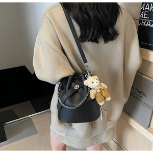 Detail der schwarzen Beuteltasche mit Lederstruktur, Silberkette und kleinem Teddy-Anhänger