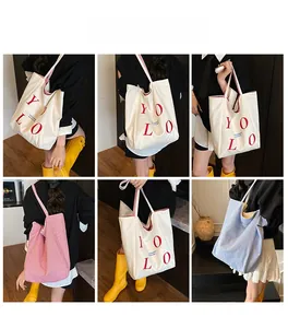 Multiple views of large striped canvas tote bag with YOLO print and bold contrast handles