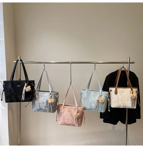 Detail of five faux leather tote bags in various colors on a display rack with bear charms