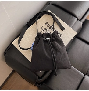 Detail of waterproof nylon drawstring bag featuring adjustable strap and side brand label