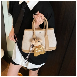 Detail of canvas tote bag with brown leather trim and cute teddy bear charm