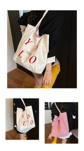 Detail view of large canvas tote bag featuring double-sided YOLO print and red stripe patterns