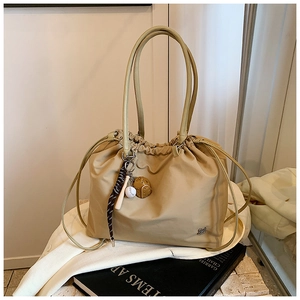 Detail of khaki drawstring tote bag featuring sports baseball charms and metal logo
