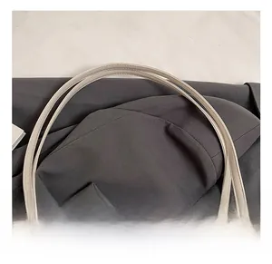 Close-up of dual slender handles and fine stitching on a beige soft leather tote bag