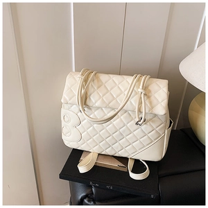 Dettaglio della trama trapuntata crema e della grande toppa B in pelle su una borsa trendy