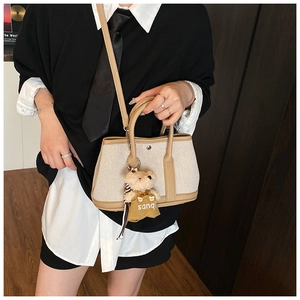 Detail of canvas and brown leather tote bag with a cute plush bear charm accessory