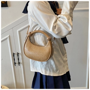 Model shot of a khaki woven dumpling bag with round handles and a detachable strap
