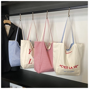 Detail view of four large canvas tote bags with stripe patterns and embroidery details