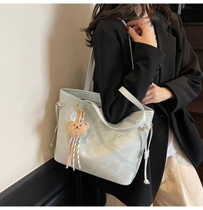 Detail view of light blue tote bag with drawstring side and cute bear plush charm