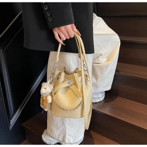 Detailansicht der gelben Eimer-Tasche mit Lychee-Muster, Kette und Bären-Anhänger