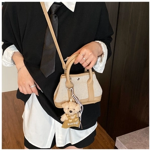 Detail of canvas tote bag with brown leather trim and cute bear plush charm accessory