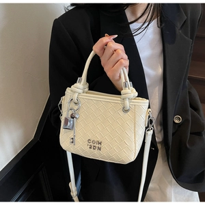 Detail of woven beige leather bucket bag featuring round handles and silver lock charm