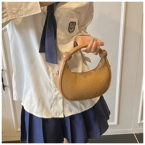 Detail of the camel dumpling bag with crocodile embossing and ball-shaped handle accents