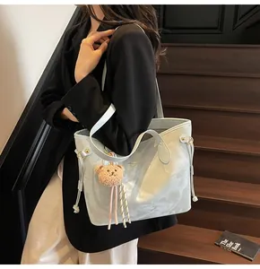Detail of light blue marble tote bag with golden logo, drawstring and brown bear charm