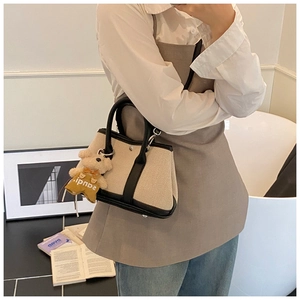 Detail of canvas tote bag featuring premium black leather trim and a cute teddy bear charm