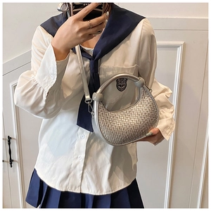 Detail of silver woven hobo bag with unique circular handle and sleek metallic texture