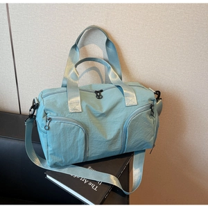 Detail of light blue nylon travel bag showing multiple front pockets and wide strap