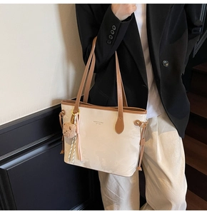 Detail of off-white PU tote bag with brown handles, brand logo, and cute bear pendant
