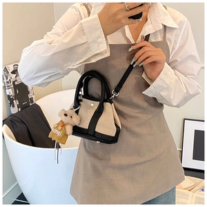 Detailed side view of mini canvas bucket bag with black leather trim and cute bear charm