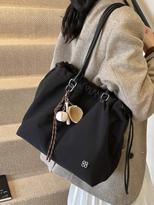 Minimalist black nylon drawstring tote bag with baseball charm and silver flower logo