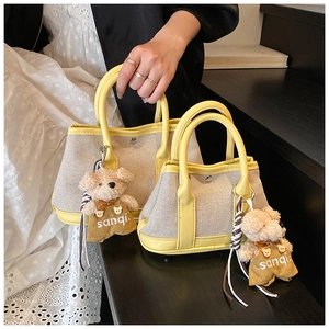 Detailed comparison of large and small canvas bucket bags with yellow leather trim and bear charms