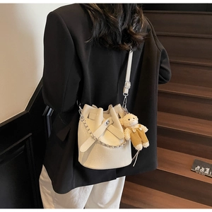 Detail der weißen Beuteltasche aus Leder mit Bärenanhänger und Umhängeriemen