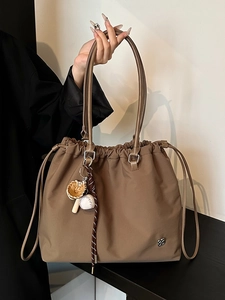 Brown nylon drawstring tote bag with shoulder straps and decorative sports charms