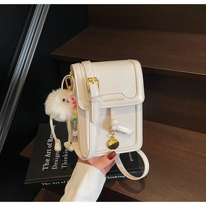 White mini crossbody phone bag with gold clasp, fashion logo, and plush charm detail