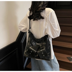 Detail of black tote bag featuring metallic silver eyelets and pearl lace charm detail