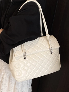 Borsa tote bianca trapuntata con design a rilievo su sfondo in legno scuro, capiente e chic