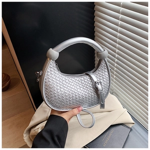 Detailed view of silver woven texture dumpling bag with circular handle and metal ball accent