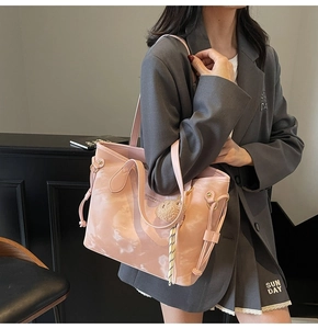 Detail of pink marble pattern tote bag with drawstring side and plush ball charm accessory